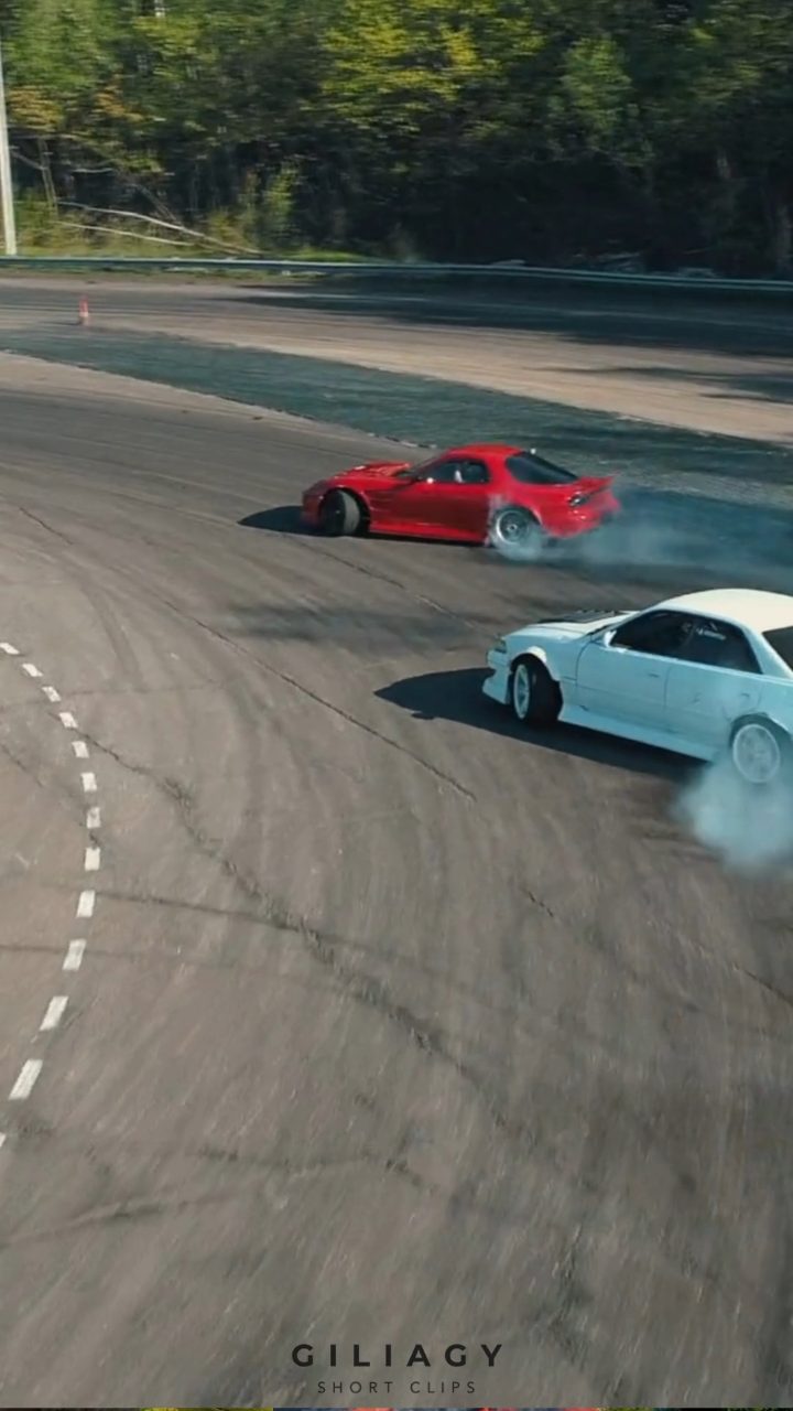 Two cars mid-drift, tyre smoke trailing behind them